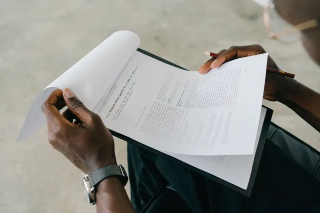 Hands holding and reviewing business documents with a pen, focusing on detailed paperwork. Ever scroll: CCPA and CPRA duties for online communities