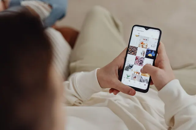 Person using smartphone to browse Instagram indoors, showing social media engagement. Digital communities: a practical guide to joining and running one
