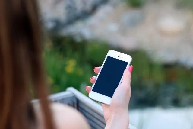 Woman using smartphone with blank screen, perfect for adding graphics. Outdoor lifestyle concept. How to review an online identity before you trust or publish it