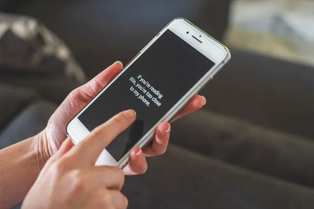 Person interacting with a smartphone indoors, emphasizing touch technology and communication. A parasocial boundaries checklist for audiences and creators
