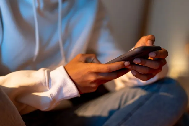 Close-up of a person holding a smartphone indoors, emphasizing digital interaction. Parasocial relationships: a practical guide