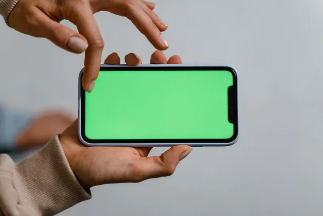 Two hands using a smartphone with a green screen, ideal for mockups. How to set boundaries around creators and online personalities