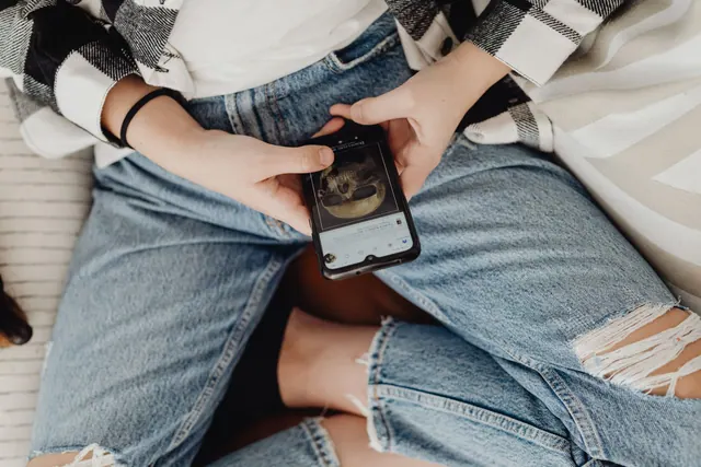 Person using smartphone while wearing casual ripped jeans indoors. What goes wrong with social media feeds, and why it keeps happening