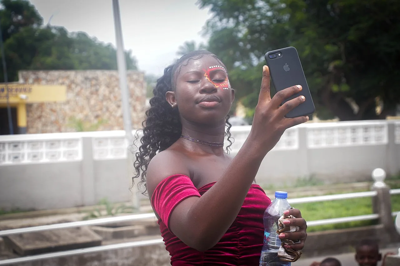 A woman taking a selfie with a smartphone at a festival in Winneba, Ghana