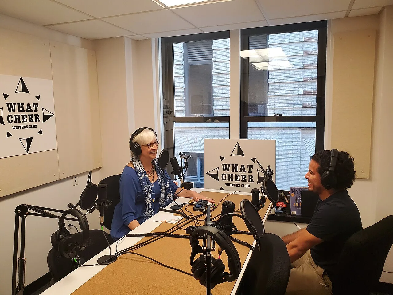 Two people recording a podcast with microphones and headphones in a studio
